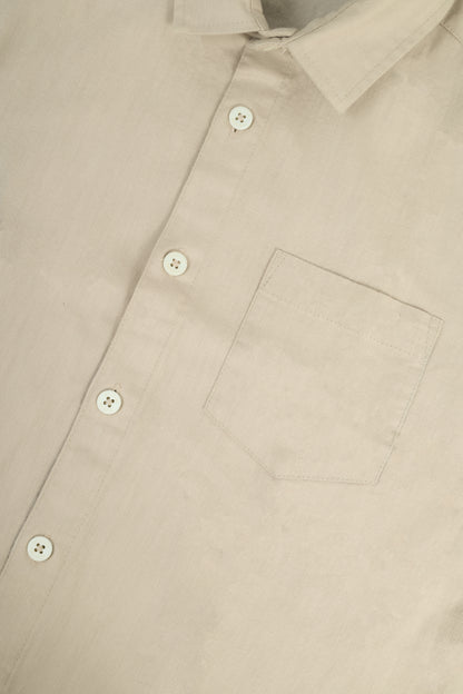 Close-up of a light beige button-down shirt showing the collar, front buttons, and chest pocket.
