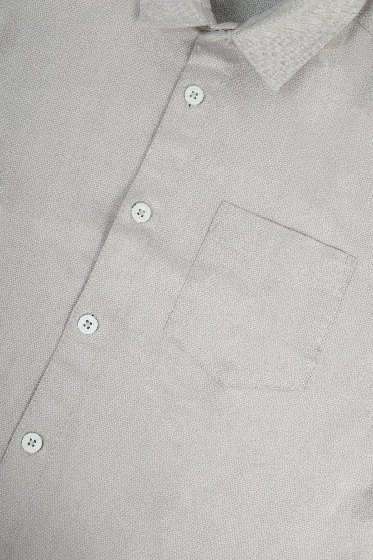 Close-up of a light gray button-down shirt showing the collar, front buttons, and chest pocket.