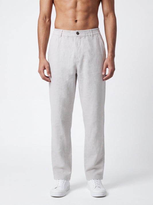 A man wearing light gray linen trousers and white sneakers, shown from the waist down against a plain white studio background.