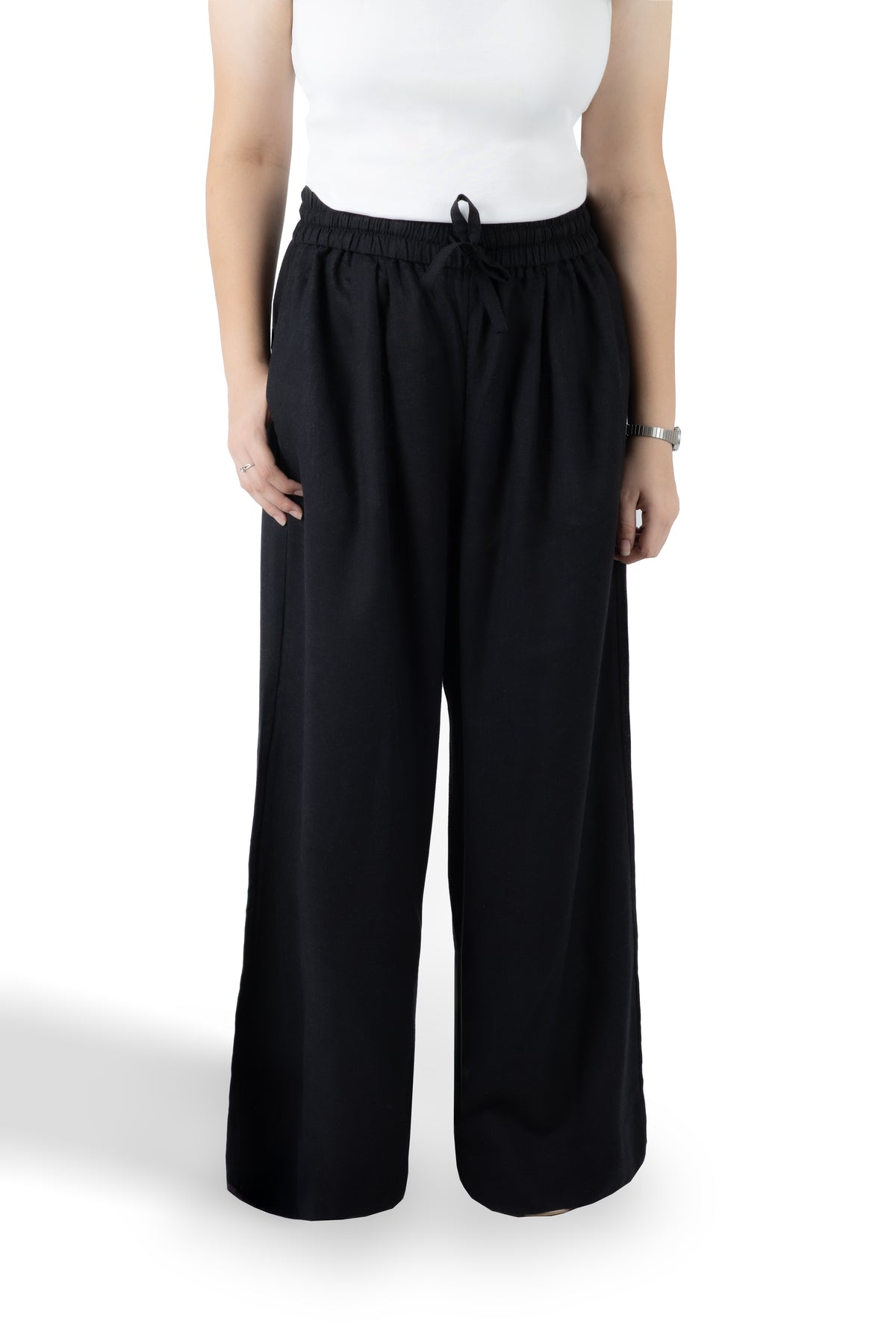 A model wearing black wide-leg drawstring pants and a white sleeveless top, shown from the chest down against a plain white studio background.